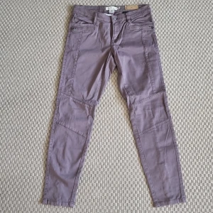 Byxor  - Ljungfärgade lågmidjade byxor med dragkedja bak på benen. Slim fit. Aldrig använda. 