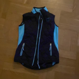 ridväst - Blå tunn ridväst. Bra om det är kyligt. Använd ca 1 gång då den var för liten för mig. Bra skick. Är ca 160 cm lång. 