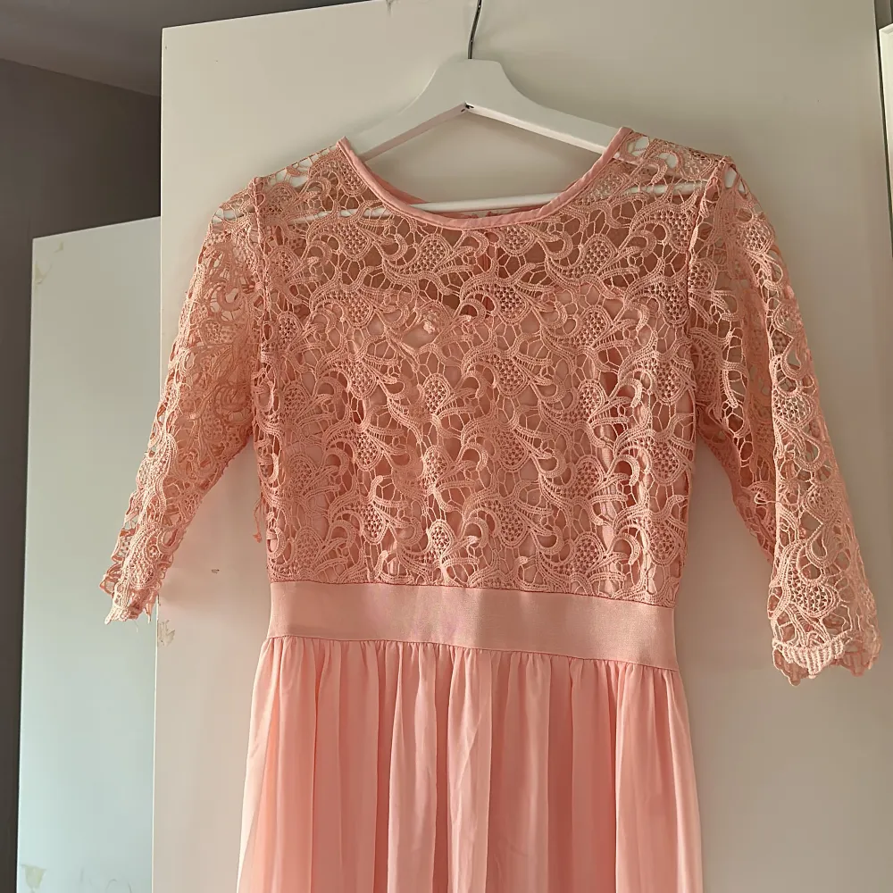 Light peach/ ljus rosa lång klänning. Den har spetsupptill och sedan en tunn lång kjol. . Klänningar.