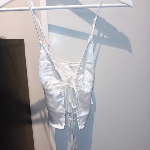 Vit silkestopp stl 34 - Säljer denna finfina topp som inte är använd, endast provad. Den är korsad i ryggen. Från H&M och storlek 34.  Finns i Växjö. 80 inklusive frakt