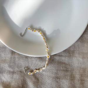 Handgjort armband med beiga stora pärlor & små vita blommor. Med silvrig kedja & lås.  70kr med kedja och lås, 60kr utan 