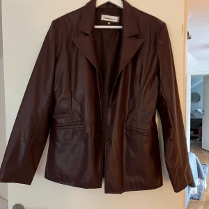 Vinröd skinnjacka - Vinröd jacka i skinnimitation, inte äkta! Jackans passform är som en oversized kavaj! Säljer pga inte kommit till använding. Köpt secondhand men i väldigt bra skick. Skriv privat för fler bilder. Frakt tillkommer☺️