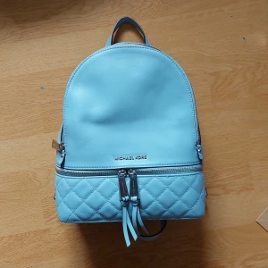 Michael Kors Väska - Säljer supersöt Michael Kors väska som inte får tillräckligt med användning! Perfekt inför sommarens resor och strosande på stan eftersom den har många fickor, lätt och bra utrymme. Den är i bra skick, använt ett fåtal ggr. Färgen är babyblå! 
