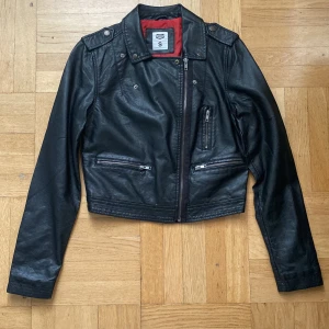 Skinnjacka - En skinnjacka som är svarta på utsidan och röd på insidan. Den är i bra skick och är snygg !