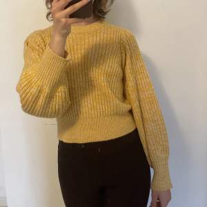 En mysig gul/orange stickad tröja. Den är en aning croppad och har ”ballong”armar. Använd fåtal gånger💕storleken fungerar även för S