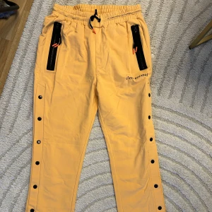 Mjukisbyxor  - Snygga Mjukisbyxor från c’est normal. Knyt i midjan och knappar som går att öppna upp längs benen. 