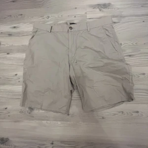Chinosshorts Slim Fit  - Storlek 34 Finns 1 par beiga på bilden men har två stycken av de beiga.  Använda fåtal gånger. Väldigt sköna chinosshorts som växt ur mig tyvärr.  Har valt svart som färg men finns både i svart och beige. 200 kr per shorts kan sänka mig vid snabb affär