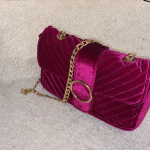 Axelremsväska  - En axelremsväska i nyskick. Finns ett innerfack med dragkedja.