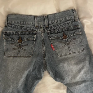 Lågmidjade jeans med coola fickor - Coolaste jeansen, med knappar och detaljer på fickorna. Sitter lågmidjade och bootcut! Säljer för att de tyvärr är små på mig ❤️