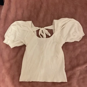 Vit topp  - T-shirt med fluff ärmar och knytning bak. Storlek s men funkar även Xs och M, stretch material 