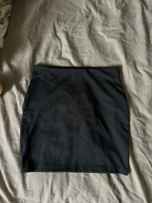 Svart kort kjol - Stretchig, kort svart kjol från cubus. Aldrig använd. Tjockt och kvalitativt tyg! Resår i midjan. Funkar att ha både high waist och low waist och på så sätt kan man styra hur lång den ska vara också. Väldigt skön men kommer tyvärr inte till användning :(
