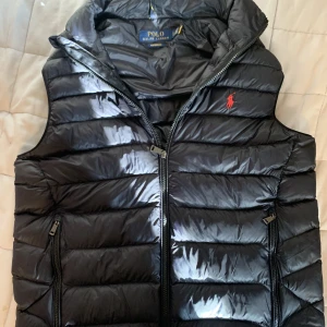 Ralph Lauren Väst - Polo Ralph Lauren Väst THE PACKABLE GILET - Svart Som är nästan alldrig använd. Condition: 9,5/10 (Inte överdrivet) Storlek: S Mitt pris 2600kr Ny pris 3200kr