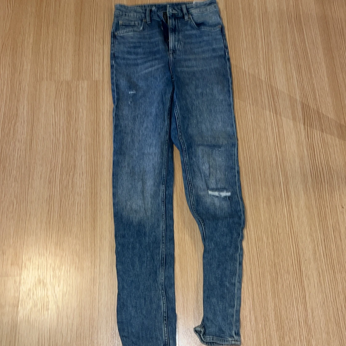 Långa blåa söndriga jeans som är högmidjade