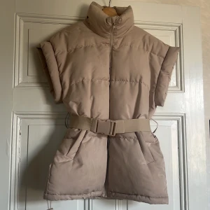 Fodrad oversize väst NA-KD strl 34 - Beige väst från NA-KD! Väldigt lite anv. Strl 34 med bältesknäppning