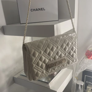 Moschino - Väldigt fin ny moschino väska med guld detaljer, rymligt stor och inte för liten. I färgen ljus beige. Tillkommer med påsen till väskan och lappar. Säljer den då jag har för mycket väskor och får bli av med dom jag inte andvänder. Pris kan diskuteras