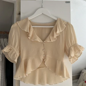 Topp/blus med volanger - Super fin beige topp från Gina tricot, liknar en blus💓💓💓💓 Hör av dig om fler bilder