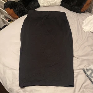 Kjol - Svart kjol i ribbat material. Har en slits vid sidan. 