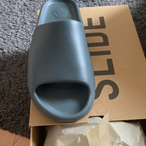 Yeeze slide slate gray - Yeeze slide köpta på Adidas CONFIRMED app. 100% äkta och helt nya! Hör av dig vid intresse. Små i storleken passar 42-43