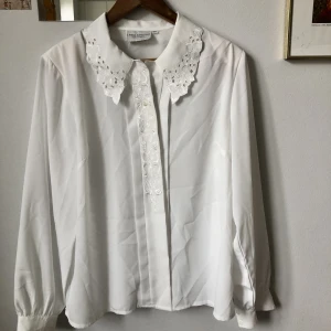 Blus med spetskrage - Vit blus med spetskrage och axelvaddar, i 100% polyester. Från en av Lindex gamla kollektioner! Storlek anges ej men jag skulle gissa på storlek L💝