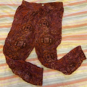 Mönstrade byxor – Urban Outfitters - Mönstrade mjuka byxor i rosa/rött/lila. Från Urban Outfitters i Berlin. Resår i midjan och vid fötterna. Storlek S