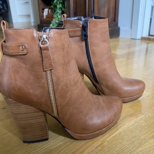 Stövletter TIAMO - Bruna stövletter med klack i trä samt dragkedja i guld. Använd en gång.  Klack 11cm