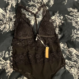 Spetsbody  - En jättefin body i spets från Nelly i storlek s. Kan användas som festtopp eller underkläder. Aldrig använd med prislapp kvar. Frakt kostar 15 kr.