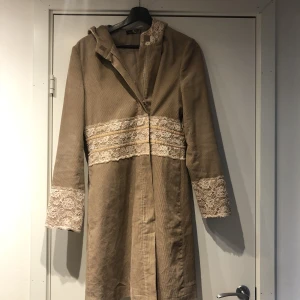 Fin kappa - Rosa/beige kappa i manchester med spetsdetaljer och luva (luvan är spetsig). Inte fodrad. Bra skick.