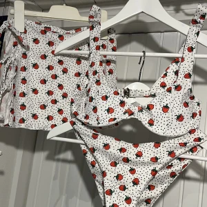 jordgubbs bikini + bikini kjol - en jättefin prickig jordgubbs bikini och en matchande bikini kjol 🍓kjolen är justerbar och knyts med snören. detta set är från shein, i storlek M. har även en likadan i storlek S. toppen ger inte mycket support och skulle passa mindre kupor :) kp för mått