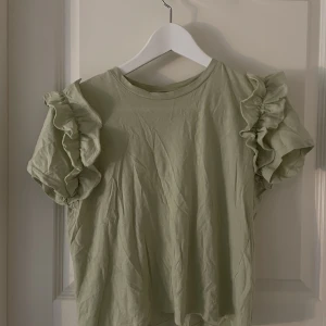 Volang T-shirt  - Säljer denna söta T-shirten med volanger på ärmarna från zara 💗 den är väl använd men är i bra skick 💗
