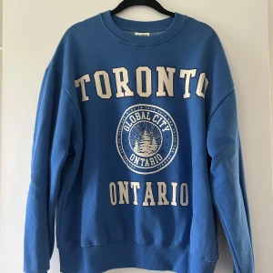 Blå swetshirt med stort tryck framtill - Blå swetshirt med stort tryck framtill. Från pull&bear storlek S. Tröjan är lite boxig modell. Använd få gånger och är i bra skick. 