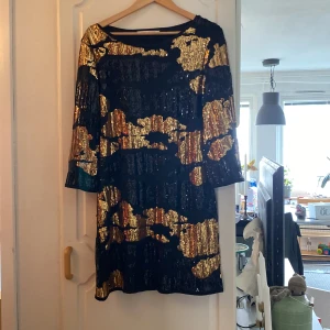Paljettklänning  - Paljettklänning i fint skick. Använd en gång. Svart bas med svarta och guldiga paljetter. 