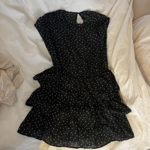 Klänning - Vitprickig svart klänning från Gina med volanger