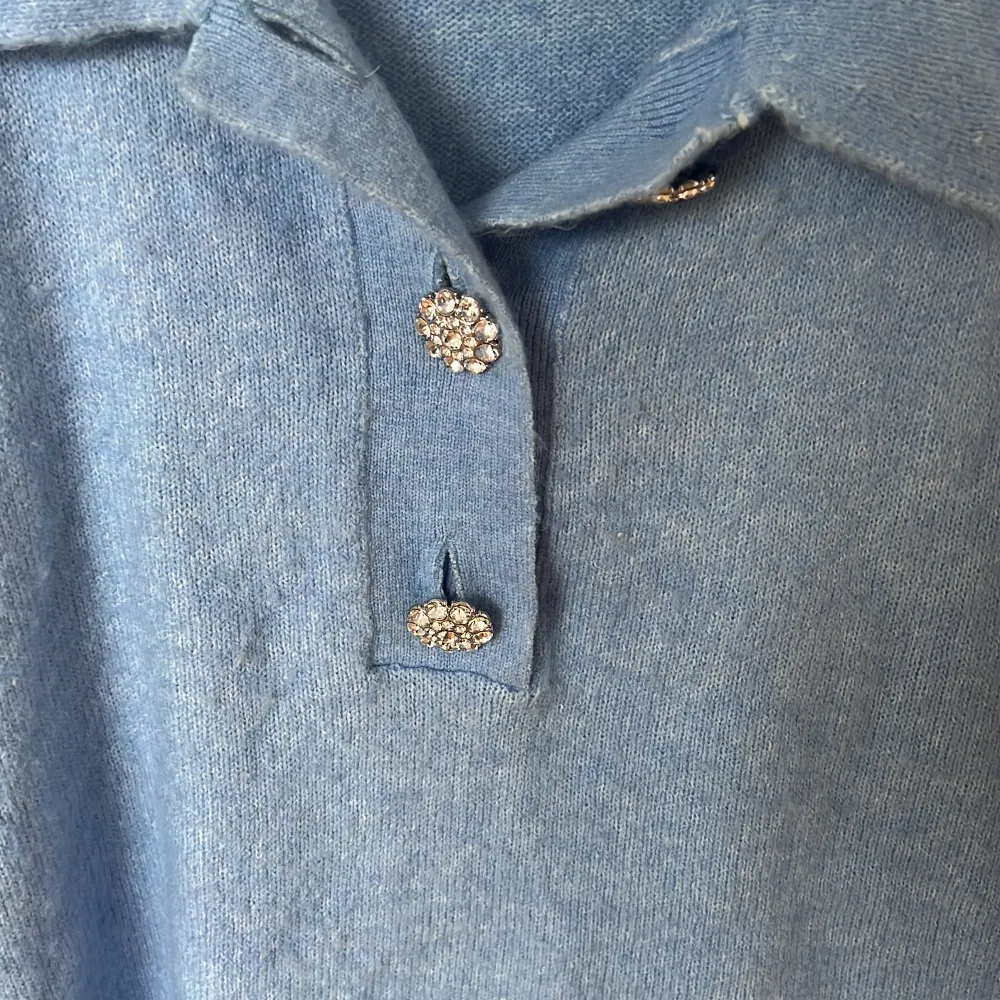 En ljusblå stickad tröja med en lite kortare arm. Silvriga knappar och en krage. Storlek xs men den är oversized så skulle säga att den passar s-m också. Väldigt fin i kvaliten och den är inte nopprig . Tröjor & Koftor.
