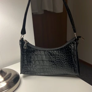 Svart handväska - Svart handväska i fake ormskinn material, som jag använde mycket för länge sedan men som är i ett bra skick ändå (lite sliten, kan visa bilder privat)!! 🩷🩷 