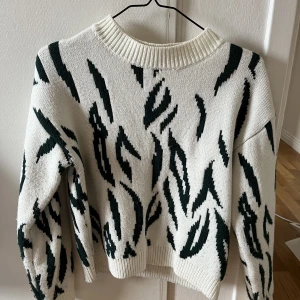 Stickad tröja - Vit stickad tröja med mörkgrönt zebra mönster. Från Nakd.