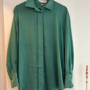 Fin grön satinskjorta från H&M. Lite Oversize look så passar stl S-L skulle jag säga beroende på hur man vill att den sitter. Bara använd 1 gång!