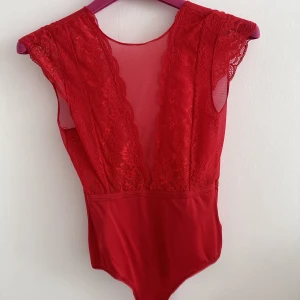 Spets body - Säljer denna röda snygga spets body som har öppen rygg. Endast använd en gång. Passar perfekt till fest!