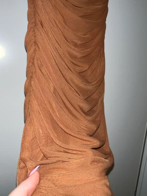 Brun tajt klänning  - Väldigt fin den kommen ner till vaderna men inte mer hela vägen. Ger väldigt fina former. 