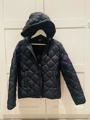 Dunjacka Gant strlk170 - Passar ungdom 13-15 år. Mycket fint skick, knappt använd dunjacka. Strlk 170cm (15y). Färg mörk marinblå, nearly black. Löstagbar luva