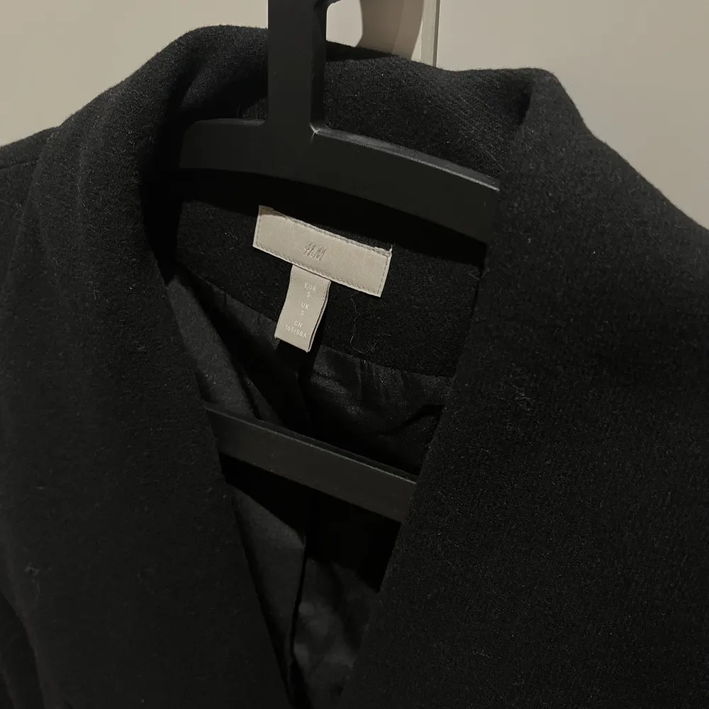Säljer denna svarta kappa med bälte från HM. Perfekt till höst och vår! Storlek S, är i nyskick och är INTE nopprig. Passar S och XS. Jackor.