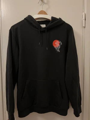 Svart hoodie med tryck - En svart hoodie med tryck från märket Pier One. Plagget är i L ite tunnare material, fint skick. Storlek M