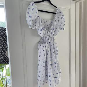 En vit klänning med blåa blommor på från H&M. Har ”cutouts” på sidorna. Perfekt för festligare tillfällen! 