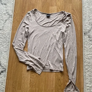 Topp från Gina beige  - En långärmad topp i storlek S beige från Gina Tricot med liten slits vid ärmslut 