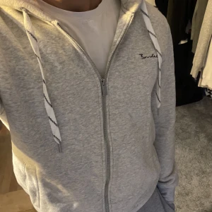 Bondelid zip hoodie - En grå bondelid zip hoodie säljes i grymt skick. Inte använd särskilt mycket.  Nypris 799 kr.