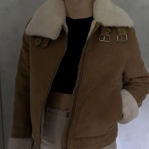 Vinterjacka - Sparsamt använd vinterjacka i brunt/beige mocka-aktigt material med fluffig krage och fluffiga ärmar. Insidan är fordrad med samma fluff. 