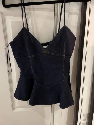 Mörkblå peplum denim topp zara - Snygg mörkblå linnetopp med smala axelband och peplumvolang nedtill. Toppen har markerade sömmar och v-ringad halsringning som ger en trendig siluett. Perfekt att styla med jeans eller kjol för en cool look. Från zara aldrig använd 💓 passar s också 
