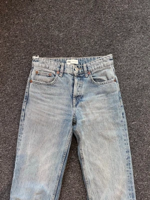 Ljusblå raka jeans från Zara - Ljusblå jeans från Zara med rak passform och klassisk femficksdesign. Jeansen har en vintage tvätt och råa kanter vid bensluten för en trendig look. 
