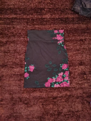 Svart blommig kjol från Indiska - Svart minikjol från Indiska med rosa blommor och gröna blad. Köptes för 50 kr
