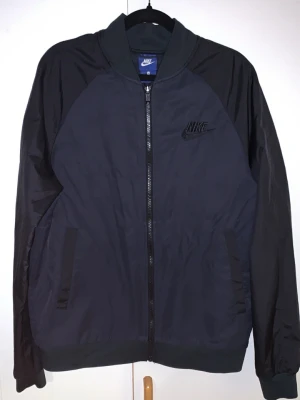 M. Nike jacka  - Har ägt den bara i 45 dagar inga skador eller hål säljer för har köpt nu Nike tech fleece Max haft på mig den 11 totalt 50 timmar totalt 4 fickor Snygg svart marinblå bomberjacka från Nike med diskret logga på bröstet. Jackan har dragkedja framtill, ribbade muddar och två sidofickor. Tillverkad i ett lätt och slitstarkt material som ger en sportig look.