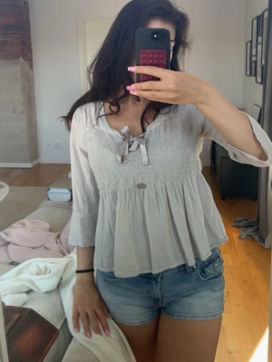 Ljusbeige blus med knyt och volang - Supersöt ljusbeige blus med knytband vid urringningen och volang nedtill. Blusen har trekvartsärmar Perfekt till jeans eller kjol💞 